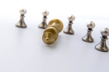 chess game - pawns circled around a fallen king