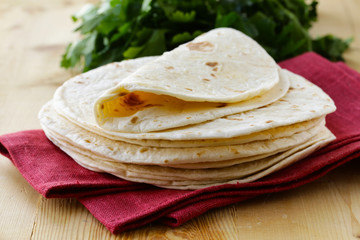stack of homemade whole wheat flour tortillas on a wooden table © Olga Kriger
