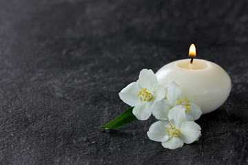 Obraz na płótnie Canvas Jasmine flowers and burning candles for spa on a black