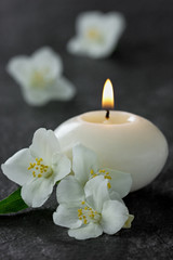 Fototapeta na wymiar Jasmine flowers and burning candles for spa on a black