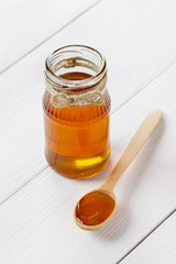 Honey in a wooden spoon and jar on a white background