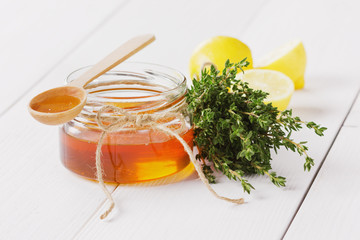 Honey in a wooden spoon and jar on a white background