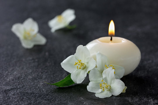 Jasmine flowers and burning candles for spa on a black