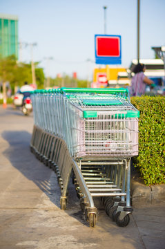 Row of shopping cart with green handles on parking near supermar