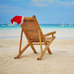 Santa hat on chaise longue on white sand beach
