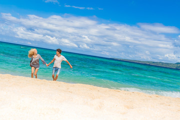 Fototapeta na wymiar young happy couple running by sand beach on tropical sea backgro