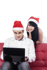 Woman in santa hat see her boyfriend with laptop