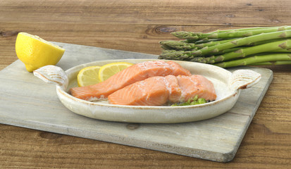 Salmon with lemon and asparagus on wooden board