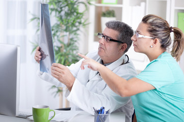 Fototapeta premium Senior male radiologist and female patient looking at x-ray