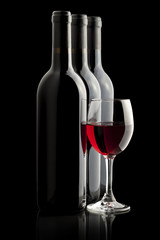 Elegant red wine glass and a wine bottles in black background