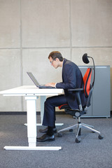 short-sighted business man bad sitting posture at laptop .