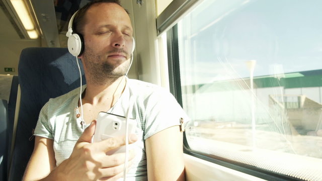 Young, handsome man listening to the music during train travel