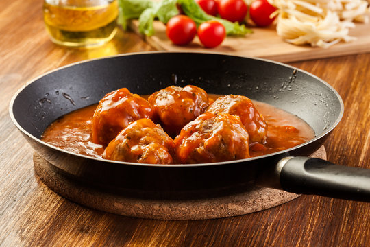 Meatballs with tomato sauce on black pan