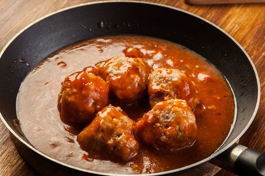 Meatballs with tomato sauce on black pan