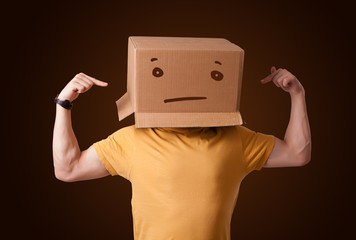 Young man gesturing with a cardboard box on his head with straig