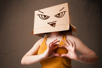 Young woman gesturing with a cardboard box on her head with evil