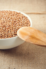 buckwheat and wooden spoon on burlap background