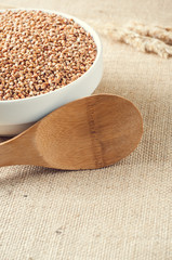 buckwheat and wooden spoon on burlap background