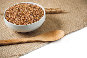 buckwheat and wooden spoon on burlap background. isolate