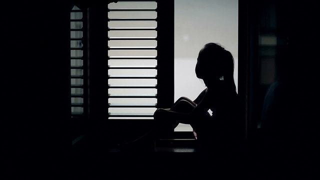 Silhouette of a child who is sitting on the sill