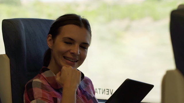 Portrait of beautiful, smiling woman with tablet during train ri