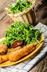 Corn dog with fresh arugula salad and hot dip