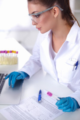 Woman researcher is surrounded by medical vials and flasks,