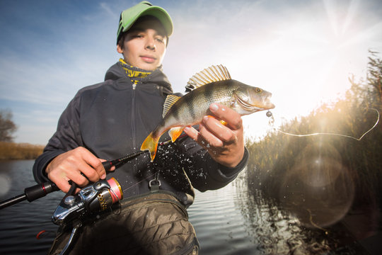Happy angler with perch fishing trophy