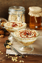 Tasty dessert with oat flakes and honey, on table