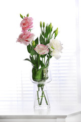 Beautiful flowers in vase on light background