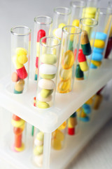 Different color drugs in test tubes, on wooden table background