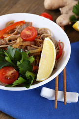 Chinese noodles with vegetables and roasted meat in bowl