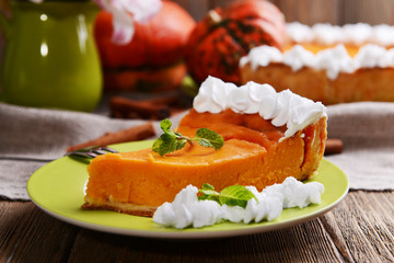 Piece of homemade pumpkin pie on plate on wooden background