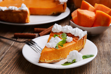 Piece of homemade pumpkin pie on plate on wooden background