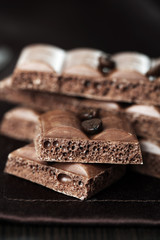 Tasty porous chocolate with coffee beans on table, close up