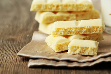 Tasty white porous chocolate on wooden table, close up
