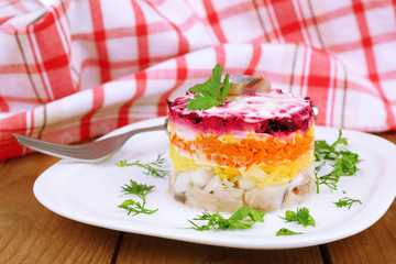 Russian herring salad on plate on wooden table background