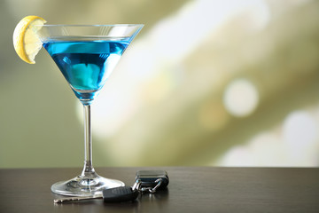 Glass of alcoholic drink and car key,