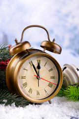 Alarm clock with Christmas decorations on light background