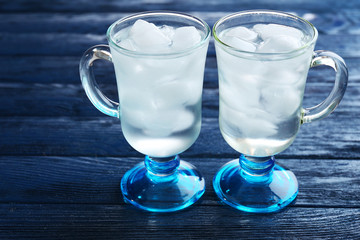 Glasses with ice cubes on wooden table