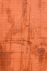 Red painted rough wooden siding board with knot