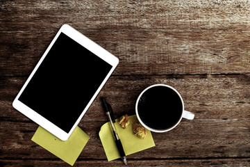 coffee and Tablet with blank notepad on old wooden table.