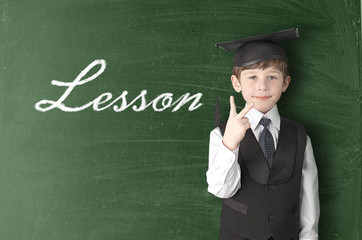 Cheerful little boy on blackboard. Looking at camera