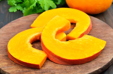 Raw pumpkin slices on cutting board