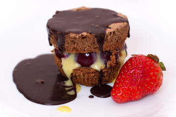 Chocolate cake on white plate with a strawberry