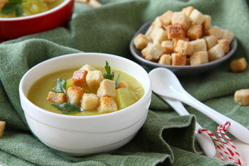 Creamy sweet potato soup with croutons and parsley in white bowl