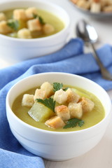 Creamy sweet potato soup with croutons and parsley in white bowl