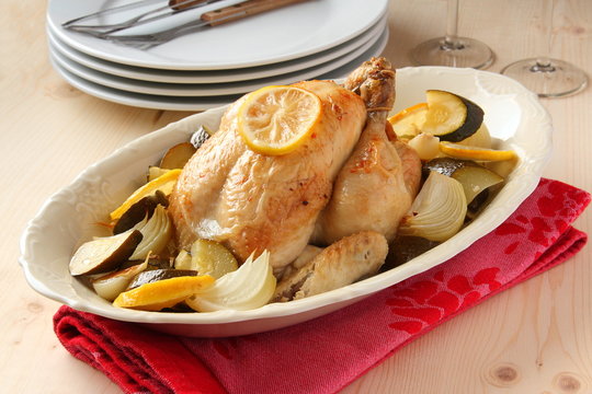 Roasted whole chicken with lemon, zucchini and onions