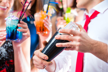 Freunde feiern mit Barkeeper in Cocktailbar