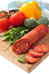 Spanish chorizo sausage with vegetables on a wooden board